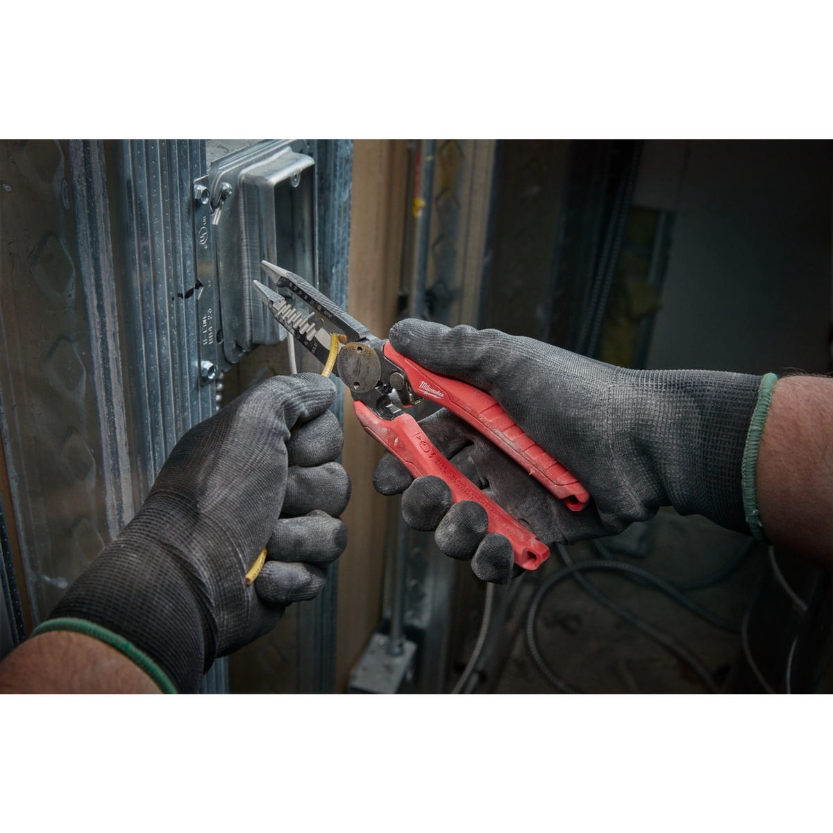 Milwaukee 48-22-3079 Combination Wire Plier cutting and handling wire in a framed wall cavity during electrical installation