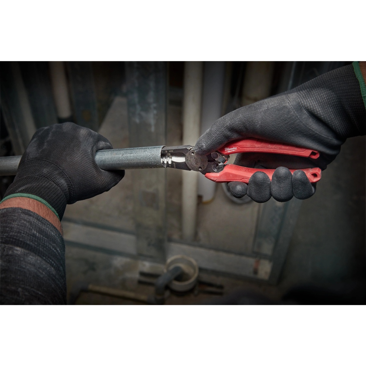 Milwaukee 48-22-3079 Combination Wire Plier reaming the inside edge of metal pipe on a jobsite while an installer holds conduit in place