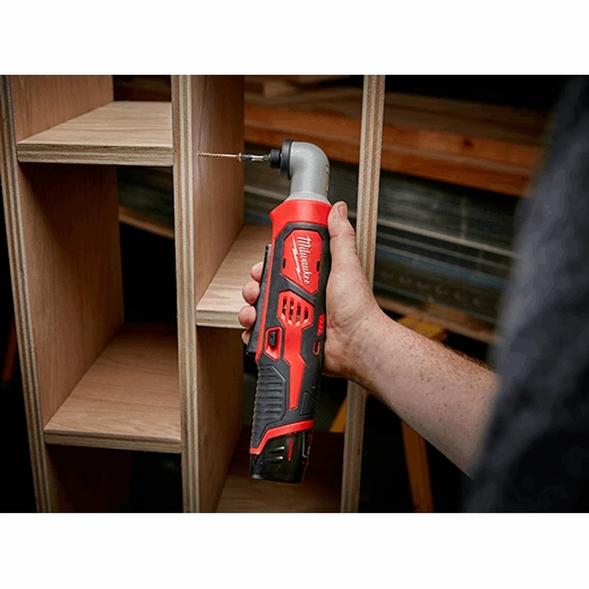 Milwaukee 2467-20 M12 1/4 inch Hex Right Angle Impact Driver driving a screw inside a plywood cabinet during installation work