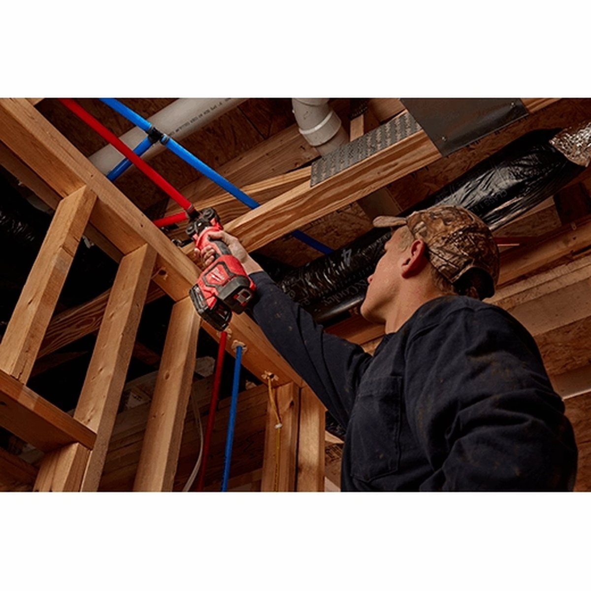 Milwaukee 2674-22C M18 Short Throw Press Tool Kit with PEX Crimp Jaws being used overhead on PEX piping inside a framed residential wall cavity during plumbing rough-in