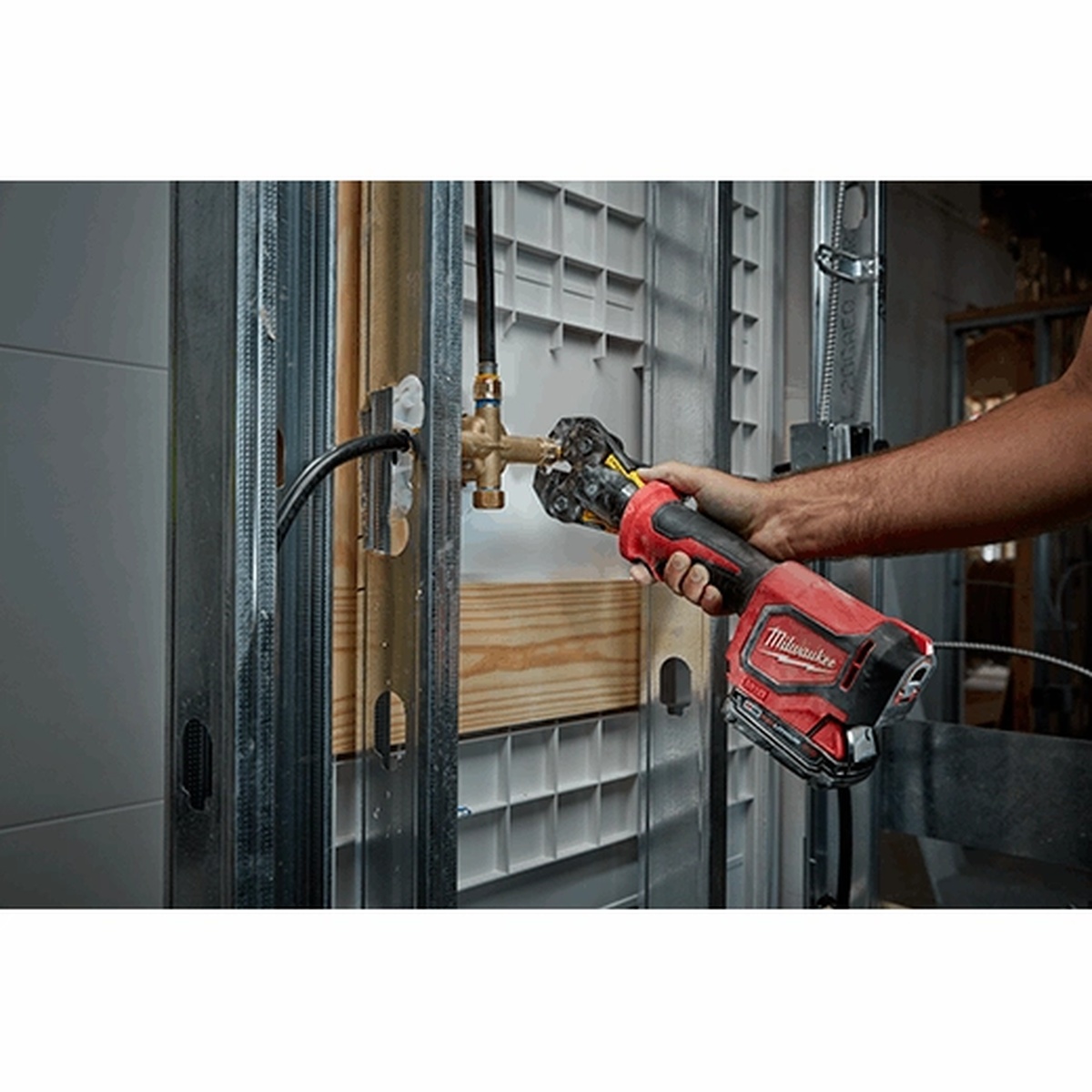 Milwaukee 2674-22P M18 Short Throw Press Tool Kit pressing plumbing connection inside a wall cavity during residential rough-in work