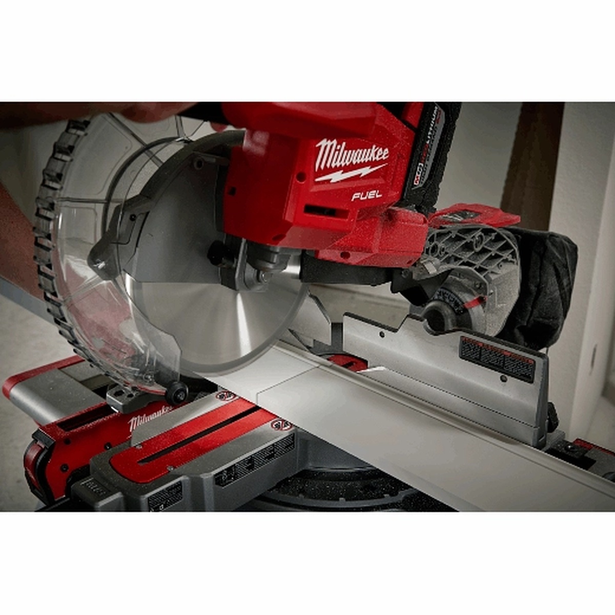 Milwaukee sliding compound miter saw cutting wide trim stock on a work stand during interior finish carpentry