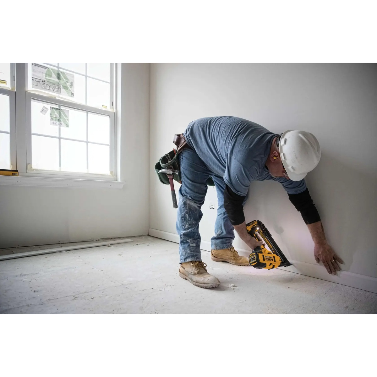 DEWALT DCN650B 20V MAX XR Cordless 15 Gauge Angled Finish Nailer fastening baseboard trim along an interior wall during finish carpentry work