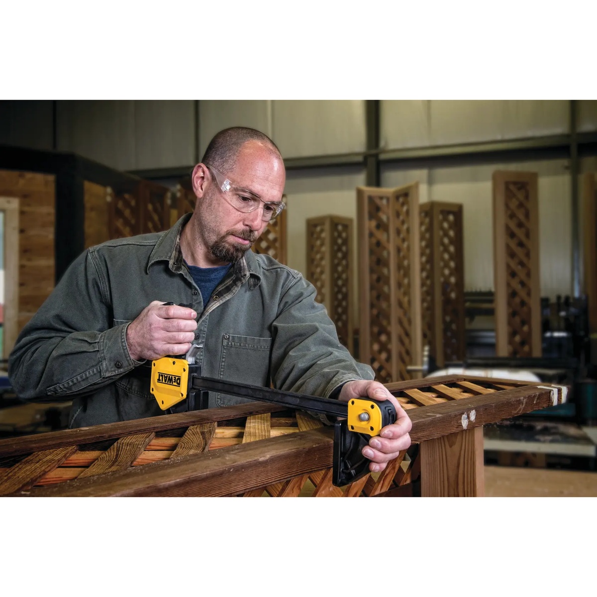 DEWALT DWHT83186 24 in. Extra Large Trigger Clamp being tightened one-handed on a wood project in a workshop