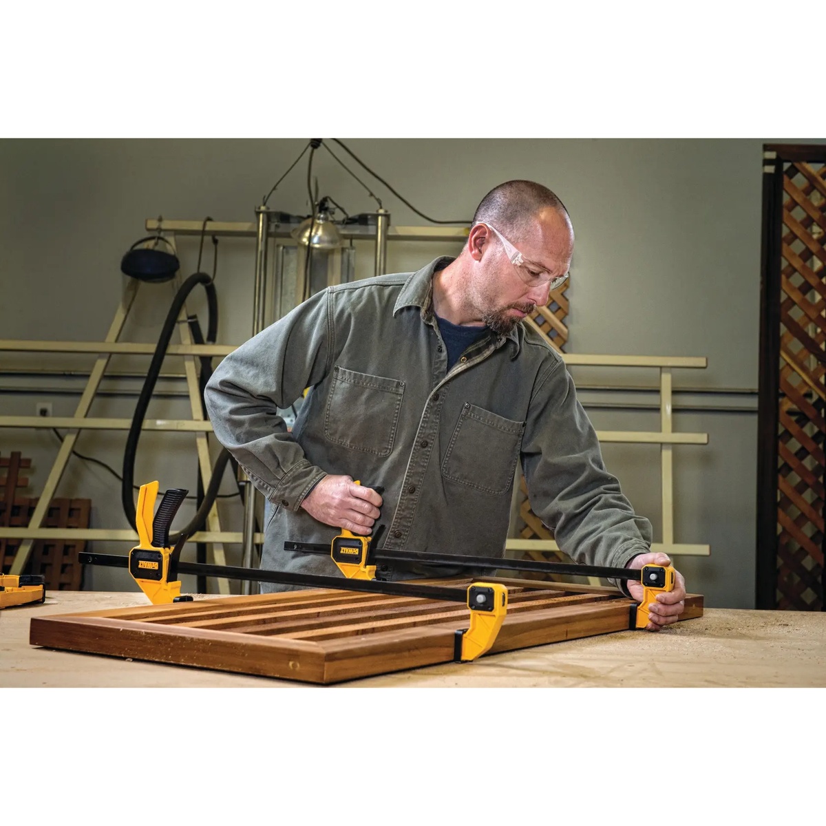 DEWALT 24-in. (600 mm) Large Trigger Clamp securing a wood panel during shop assembly on a workbench