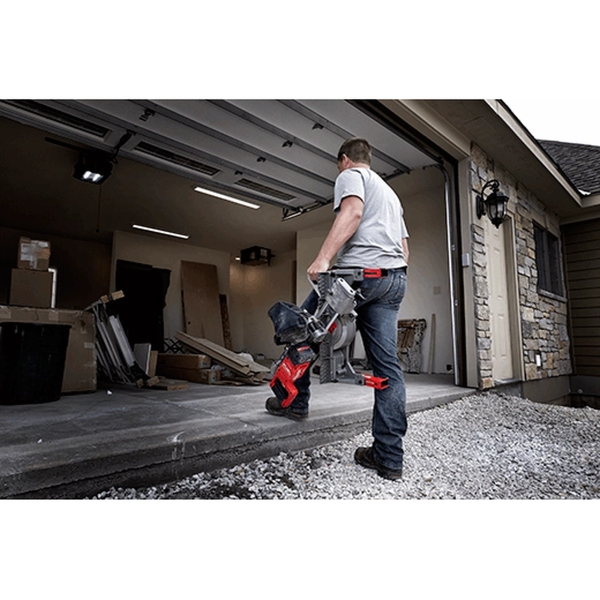 Milwaukee 2733-21 M18 FUEL 7-1/4 Dual Bevel Sliding Compound Miter Saw Kit being carried into a residential garage jobsite for trim and remodeling work