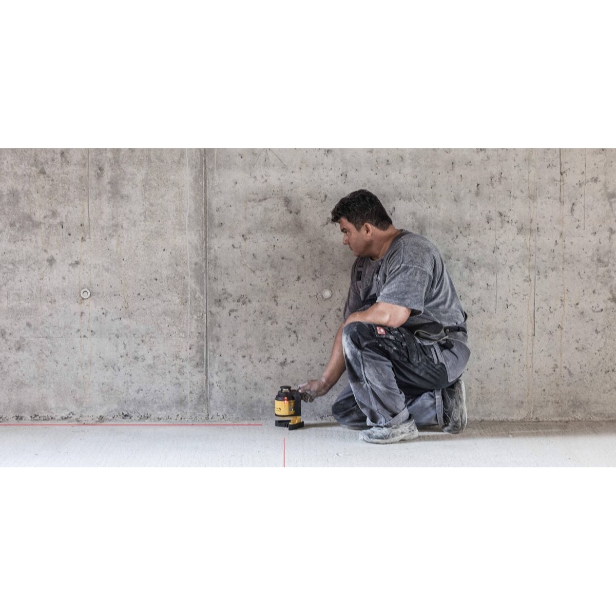 Stabila 03360 LAX 400 multi-line self-leveling laser level on the floor with a red plumb reference line for precise layout on concrete