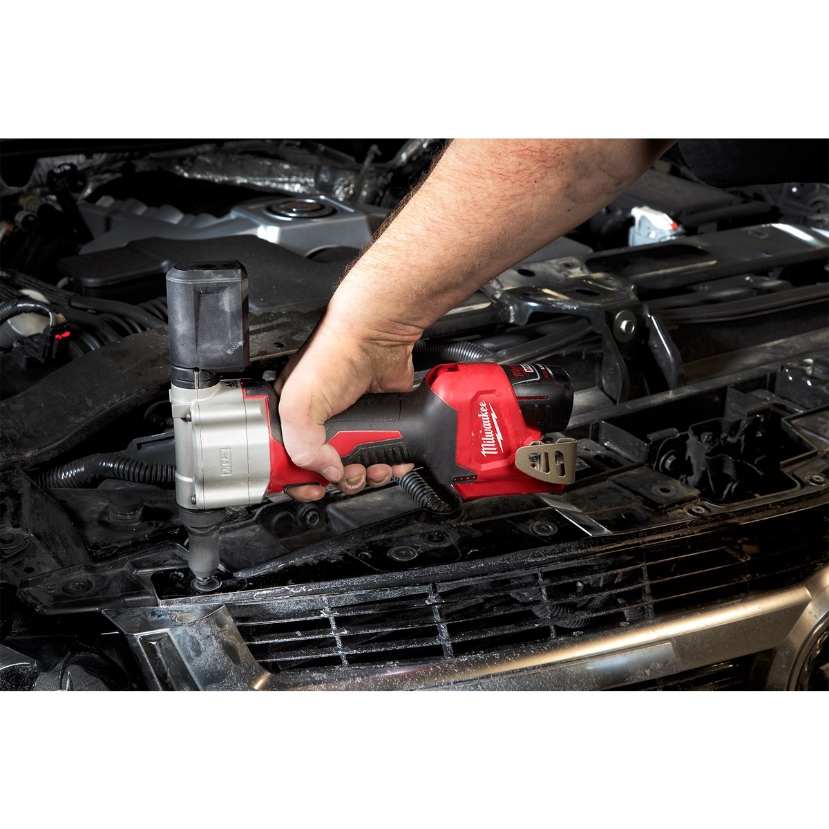Milwaukee 2550-20 M12 Rivet Tool being used in an automotive engine bay to install a rivet in tight sheet metal access