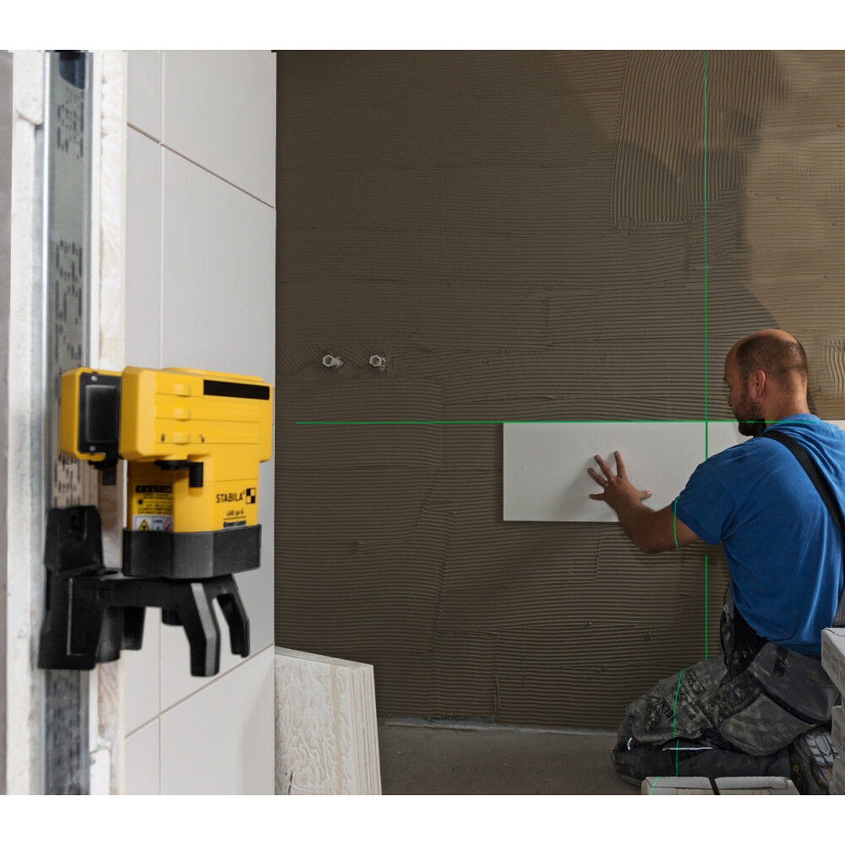 Stabila LAX 50 G Green Laser projecting horizontal and vertical green lines on an interior wall during tile installation layout work