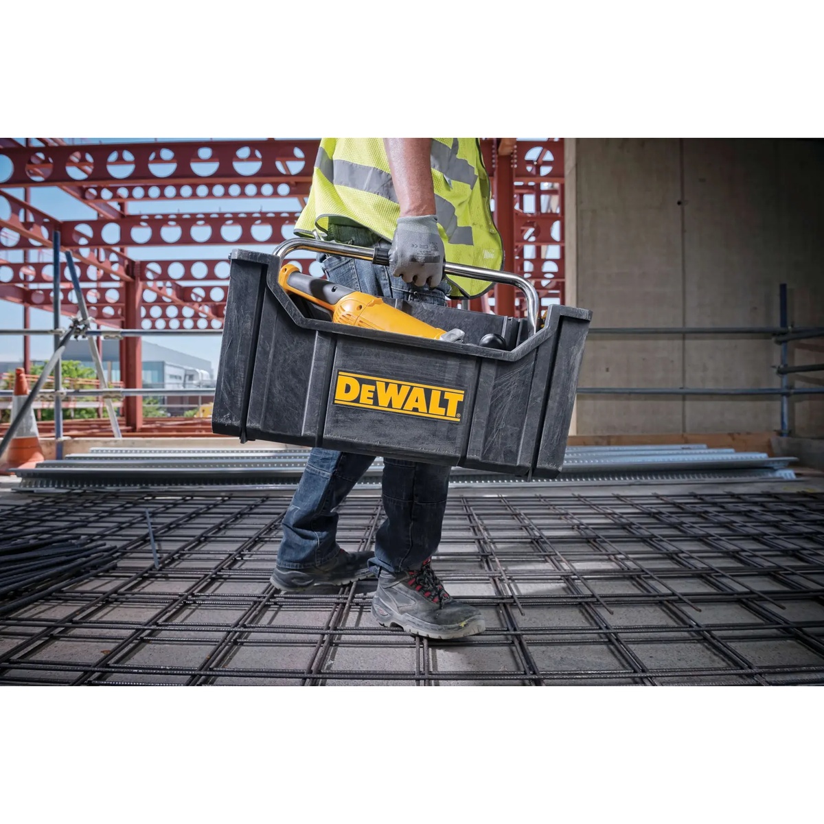 DEWALT ToughSystem Tote with Carrying Handle being carried across a construction site with tools inside for mobile jobsite storage