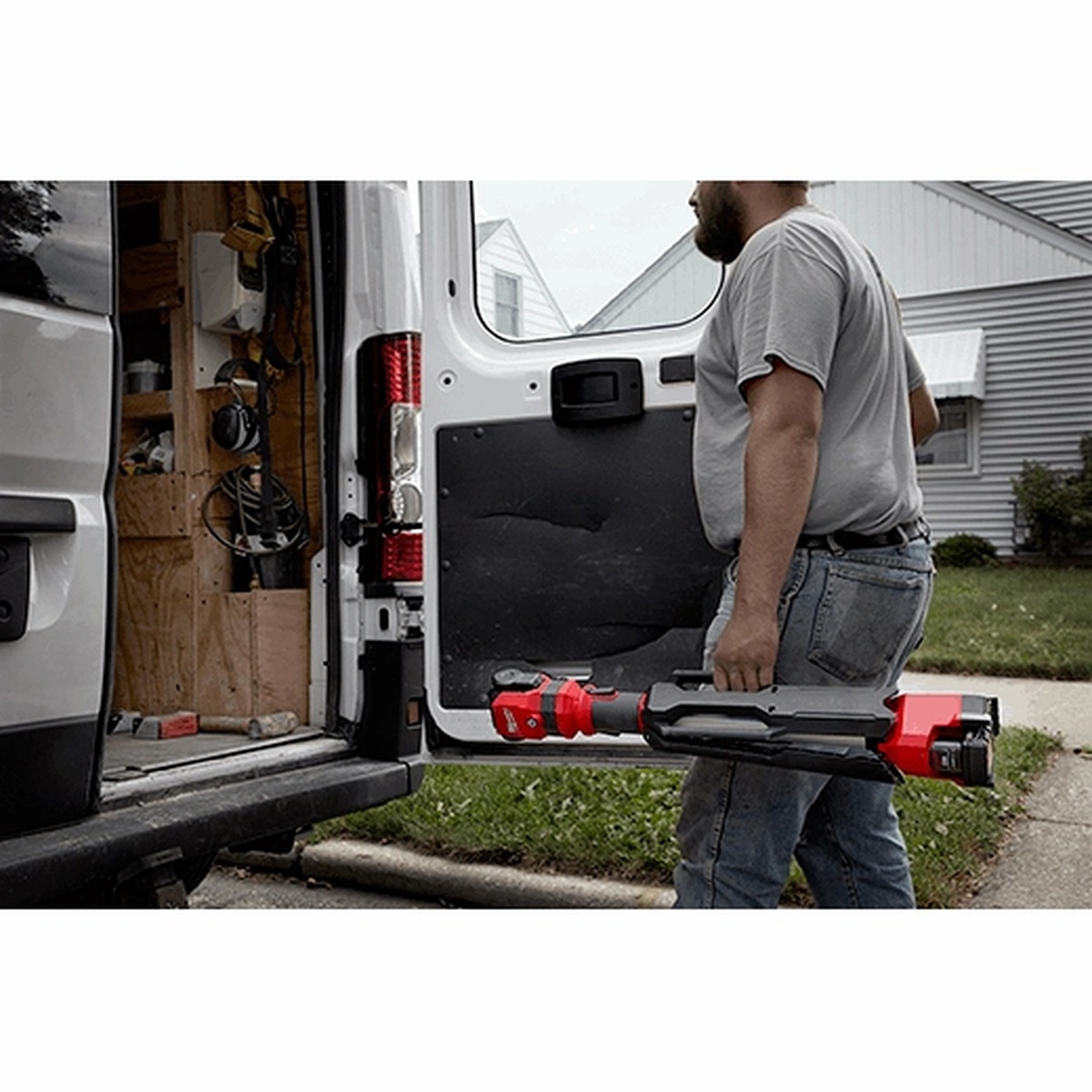 Milwaukee M12 ROCKET Dual Power Tower Light collapsed for transport beside a work van, showing compact carry size for service calls and mobile jobsite setup