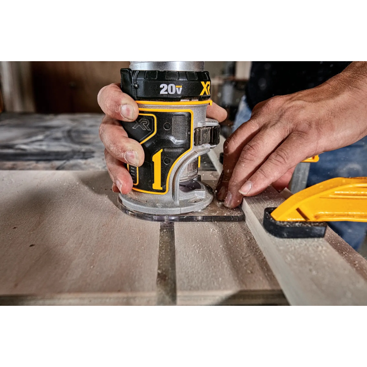 DEWALT DCW600B 20V MAX XR Brushless Cordless Router making a controlled edge pass on a wood panel at a woodworking bench
