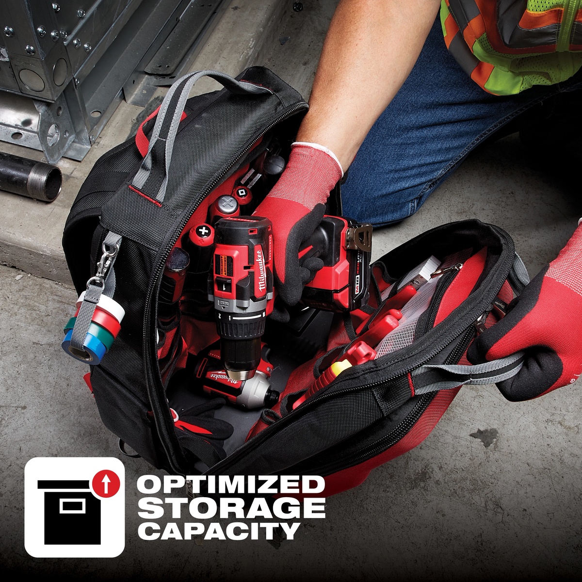 Milwaukee PACKOUT Tool and Equipment Backpack opened on a jobsite floor holding cordless tools, hand tools, and accessories during service work