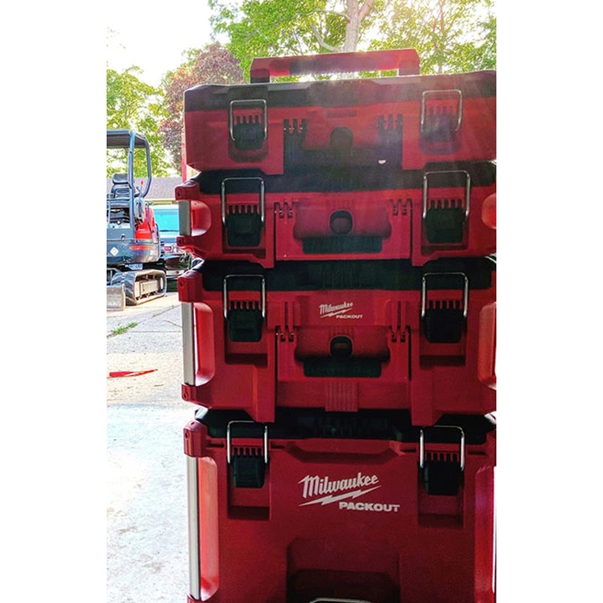 Milwaukee PACKOUT tool case stacked with other PACKOUT storage boxes in a jobsite environment for transport and organized storage