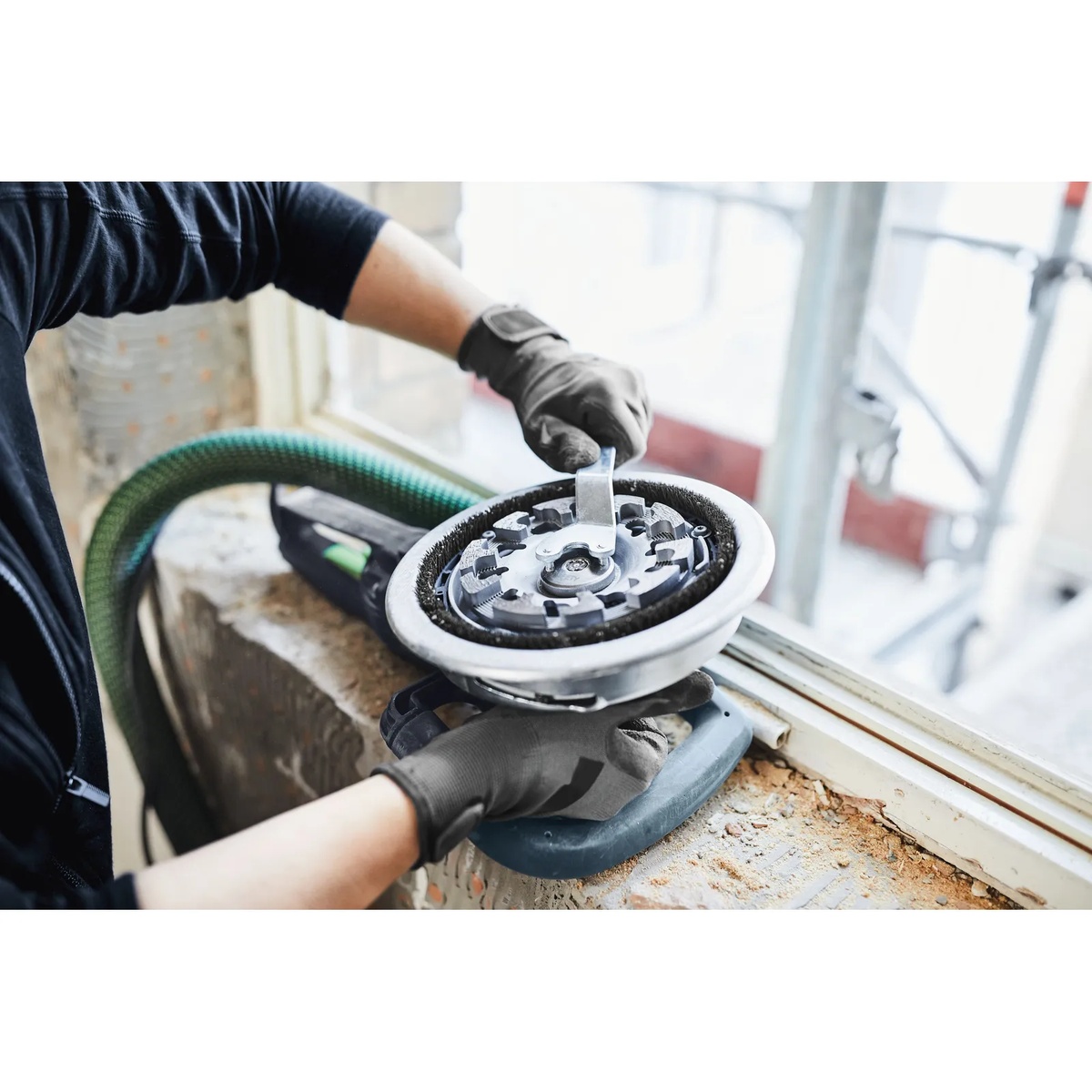 Festool 768017 DIA HARD-D130 PREMIUM Diamond Disc being installed on an RG 130 grinder at a renovation site near a concrete window opening