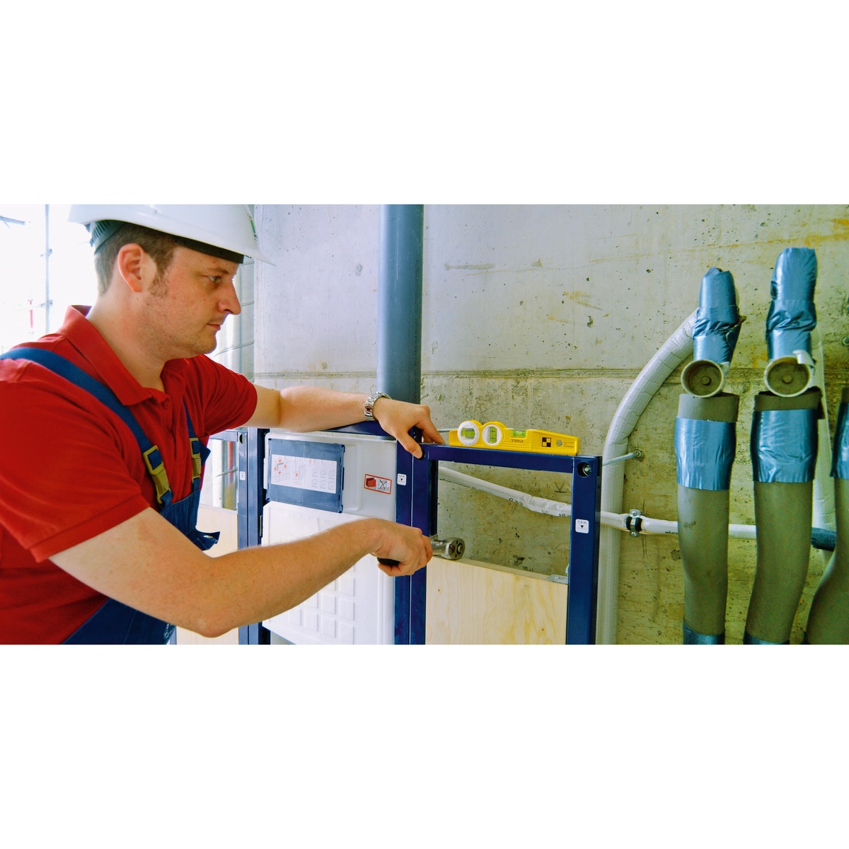 Stabila 25360 Type 81 SV REM W360° Level being used to align a metal installation frame on a jobsite wall near pipe and conduit