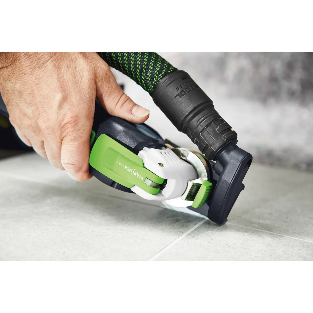 Festool diamond oscillating multi-tool blade used with dust extraction while cutting along a tile joint in a finished interior workspace
