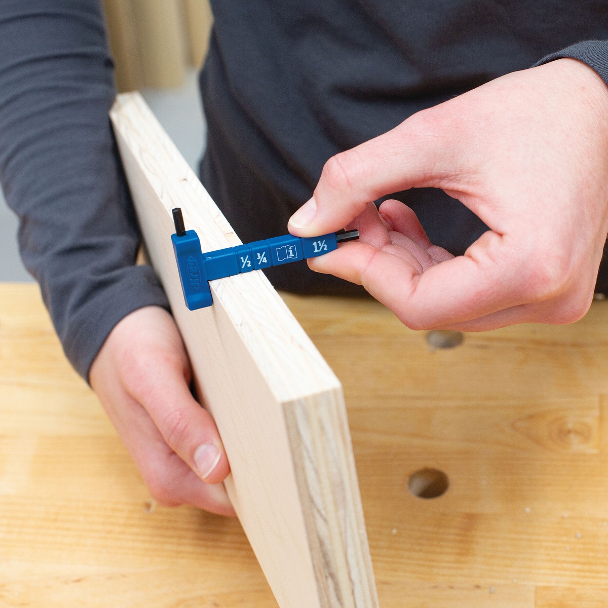 Kreg KPHA308 thickness gauge measuring a wood board on a workbench to confirm pocket-hole setup before drilling