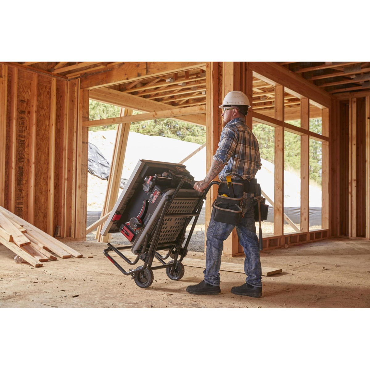 SawStop Jobsite Saw Pro table saw folded on its mobile cart being rolled through a framed construction site for transport between work areas