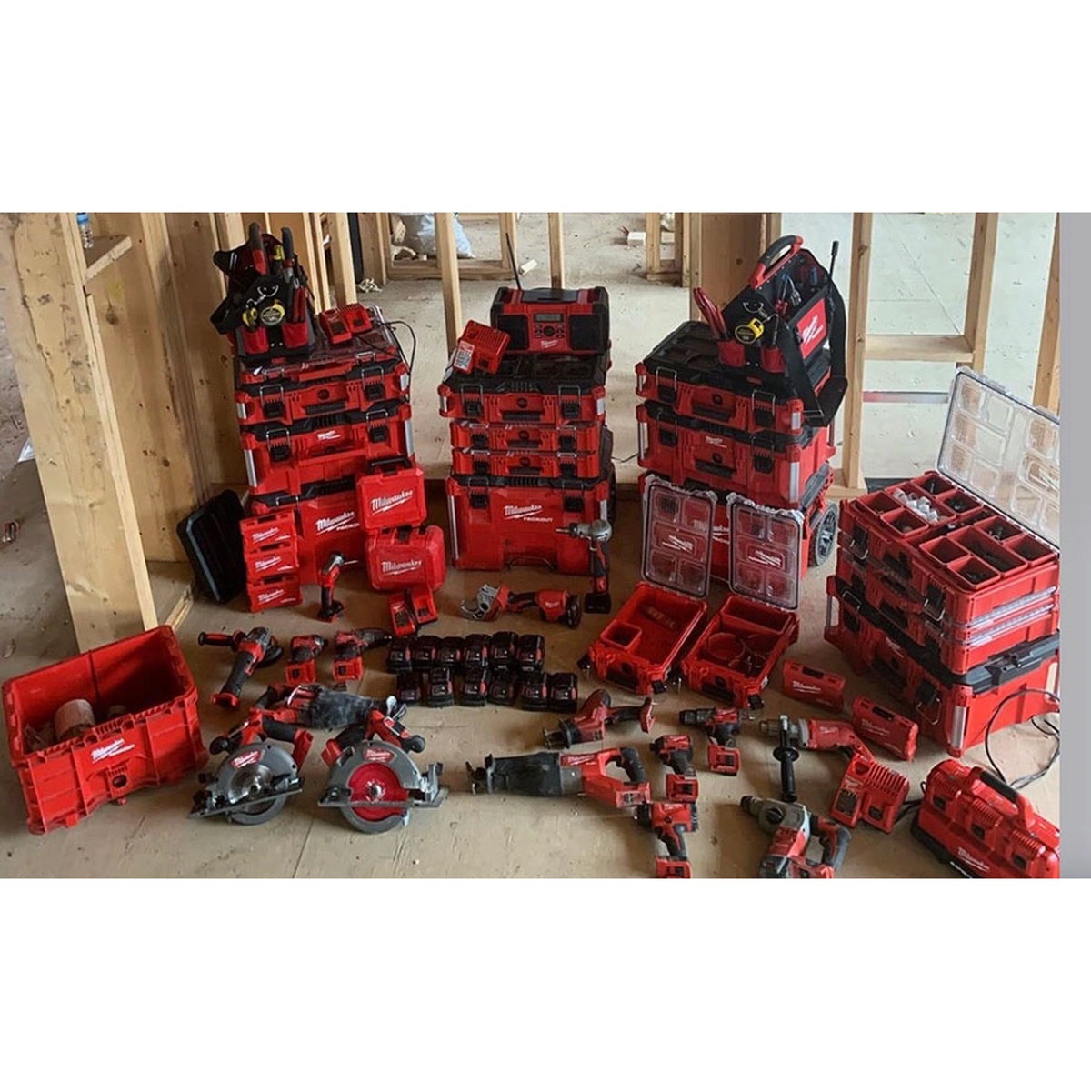 Milwaukee 48-22-8440 PACKOUT Crate on a framed construction site alongside stacked PACKOUT storage and cordless tools