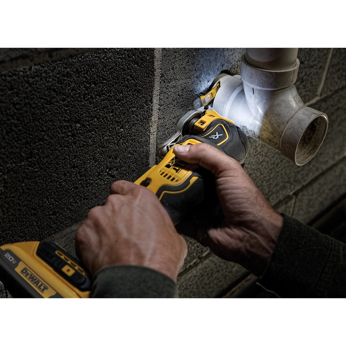 DEWALT DCS356D1 20V MAX XR Brushless Cordless 3-Speed Oscillating Multi-Tool Kit making a tight cut around plumbing pipe in a masonry wall during remodeling work