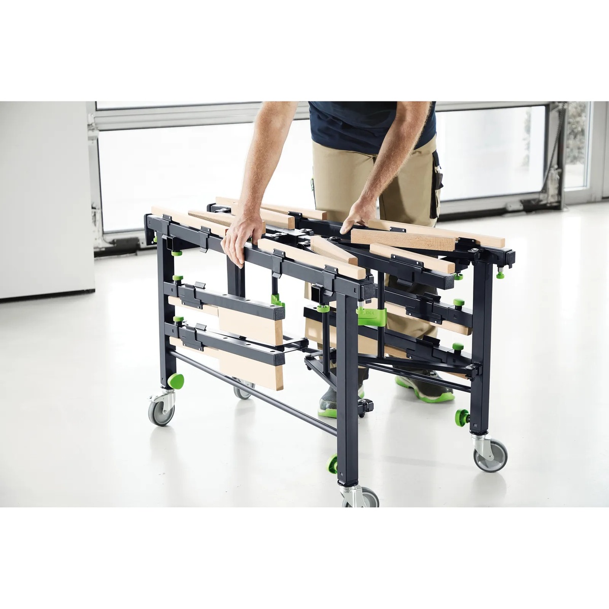 Festool STM 1800 mobile sawing table being folded for transport in a clean workshop with casters visible for mobility