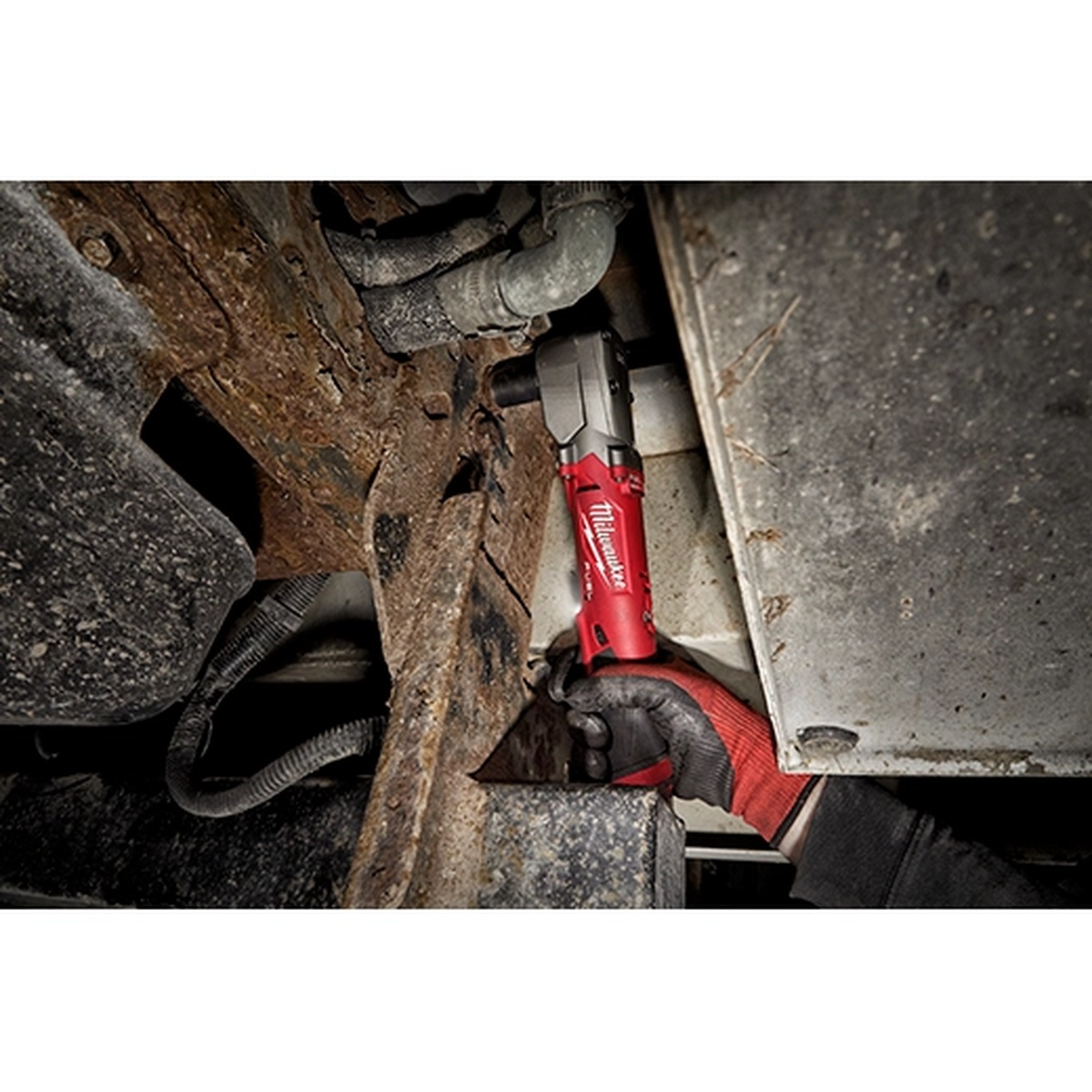 Milwaukee 2564-20 M12 FUEL 3/8 in right angle impact wrench removing a fastener in a tight underbody automotive repair area with limited clearance
