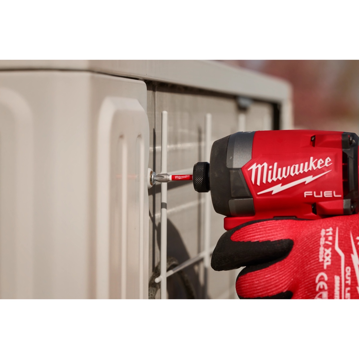 Milwaukee impact driver using a SHOCKWAVE bit to fasten a screw into an exterior equipment panel during service work