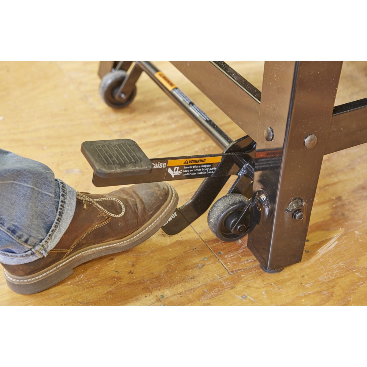 SawStop MB-CNS-000 Contractor Saw Mobile Base foot pedal being pressed by a work boot on a wood shop floor to raise and move the saw