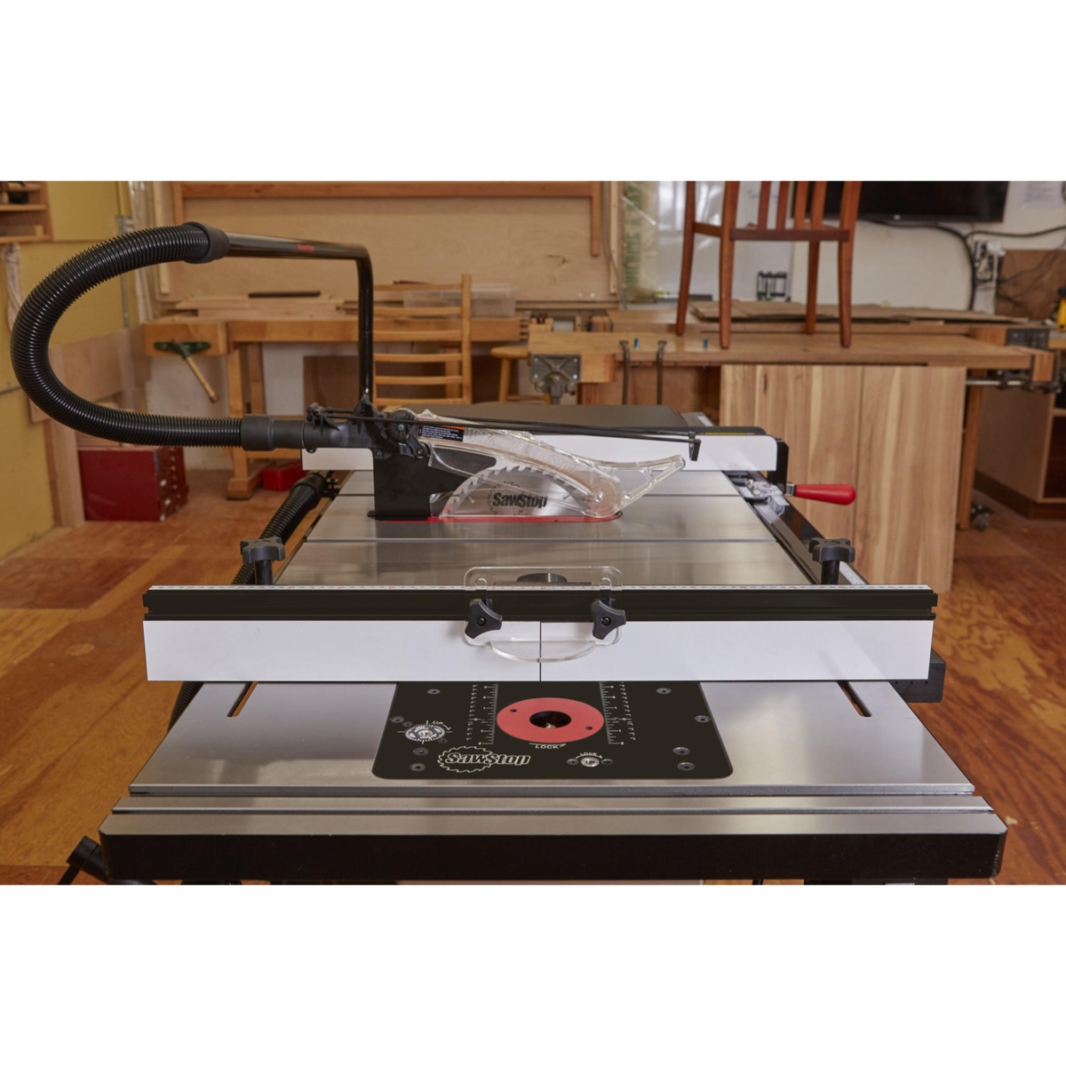 SawStop RT-TGP 27 Inch In-Line Router Table close-up showing the router insert opening, adjustable fence faces, and dust collection hose connected during woodworking setup