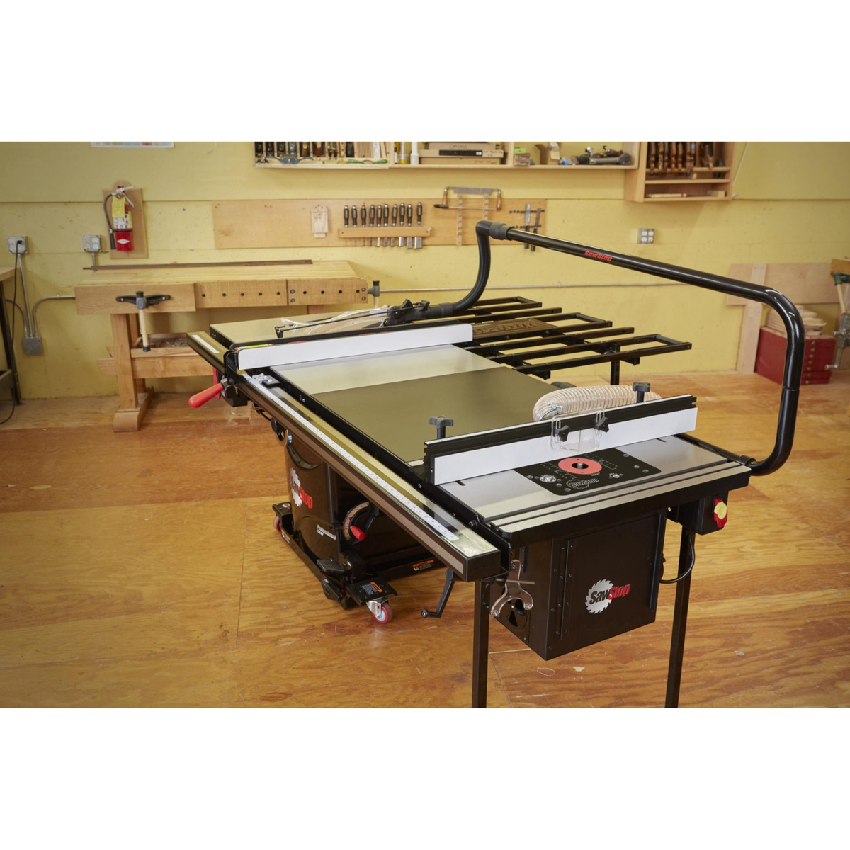 SawStop RT-TGP 27 Inch In-Line Router Table showing the cast iron top, adjustable router fence, and fence-mounted dust collection in a cabinet shop setting