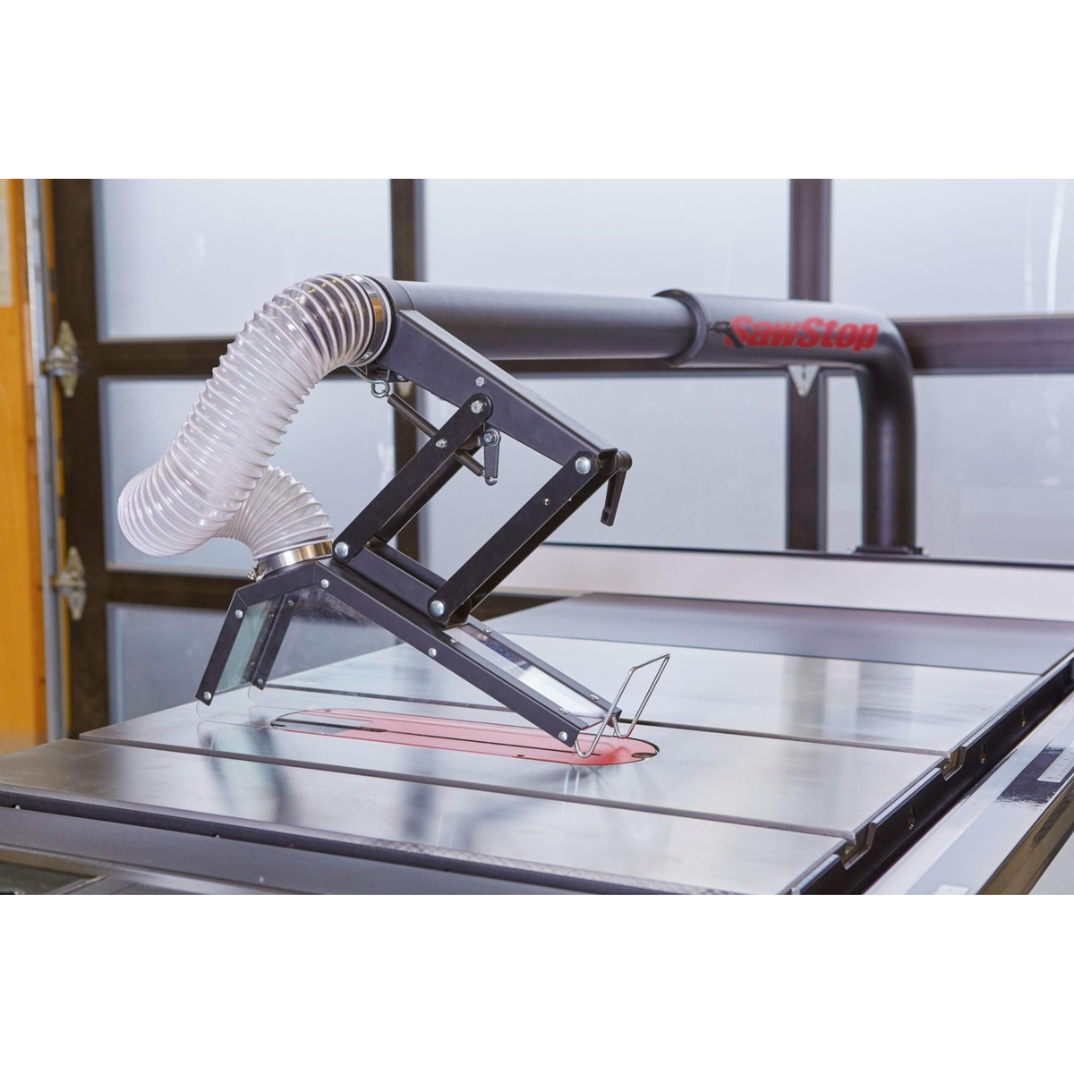 SawStop TSG-FDC Floating Overarm Dust Collection Guard installed over a table saw blade with clear guard panels and steel support arm in a workshop