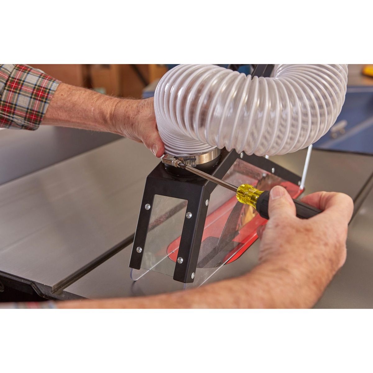 SawStop TSG-FDC Floating Overarm Dust Collection Guard close-up showing the transparent blade cover and hose connection during setup on a table saw