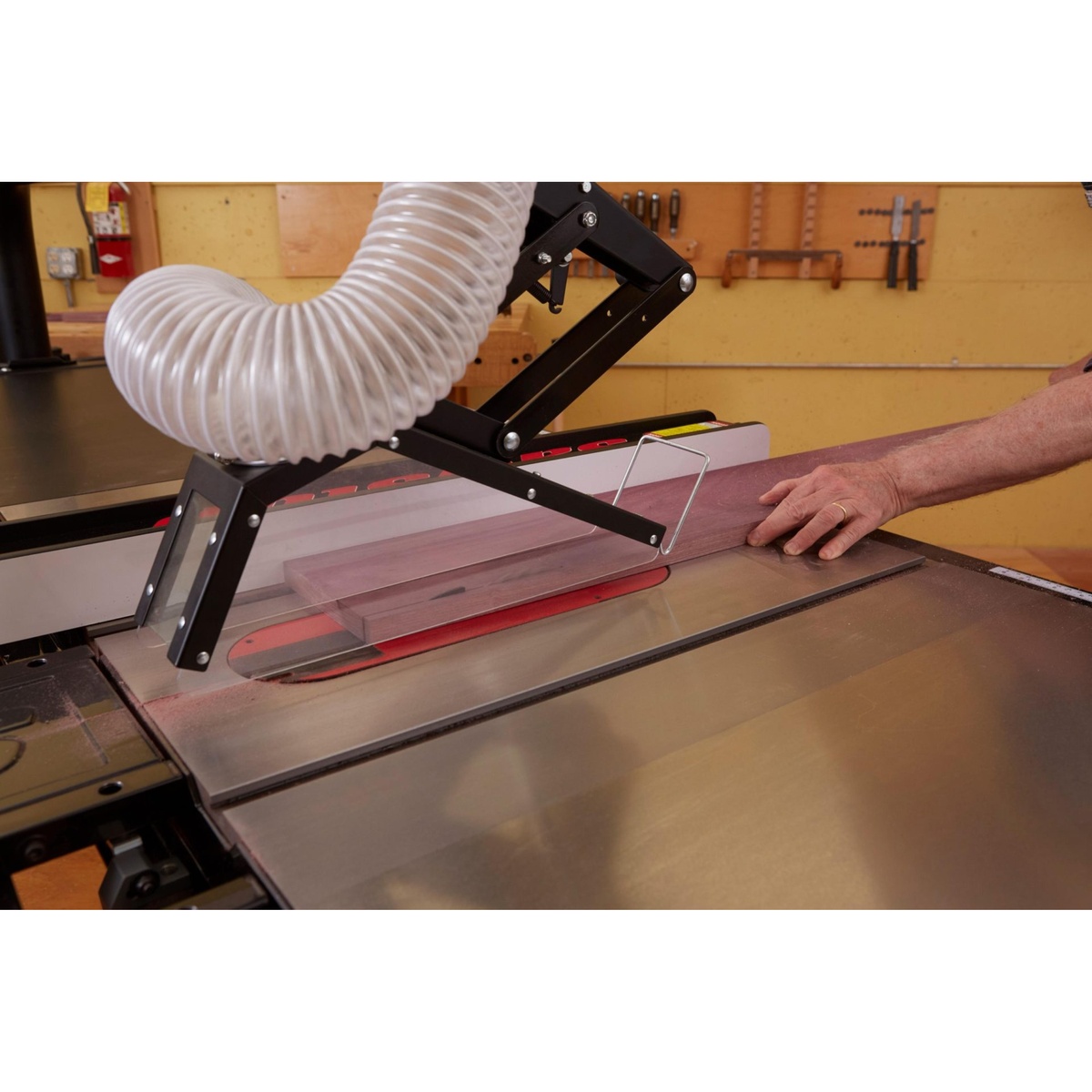 SawStop TSG-FDC Floating Overarm Dust Collection Guard collecting dust above a table saw blade while ripping a hardwood board in a woodworking shop