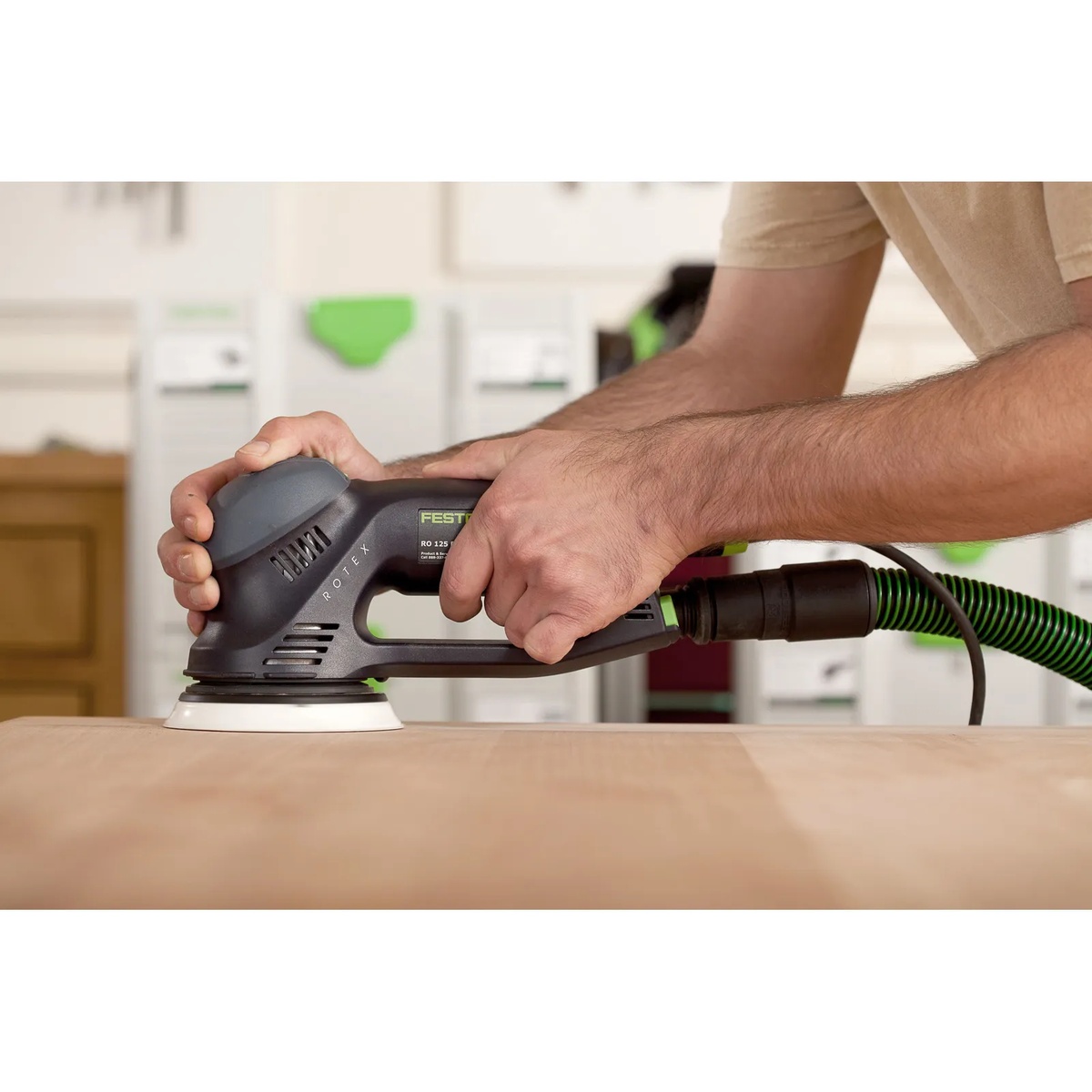 Festool 576032 RO 125 FEQ-Plus Rotex 125mm 5 inch multi-mode sander smoothing a wood tabletop in a workshop with a vacuum hose connected