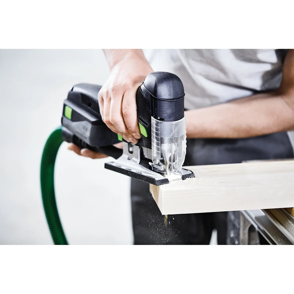 Festool cordless jigsaw cutting a wood panel with dust hose attached, showing line-of-sight cutting and cleaner work area during finish carpentry