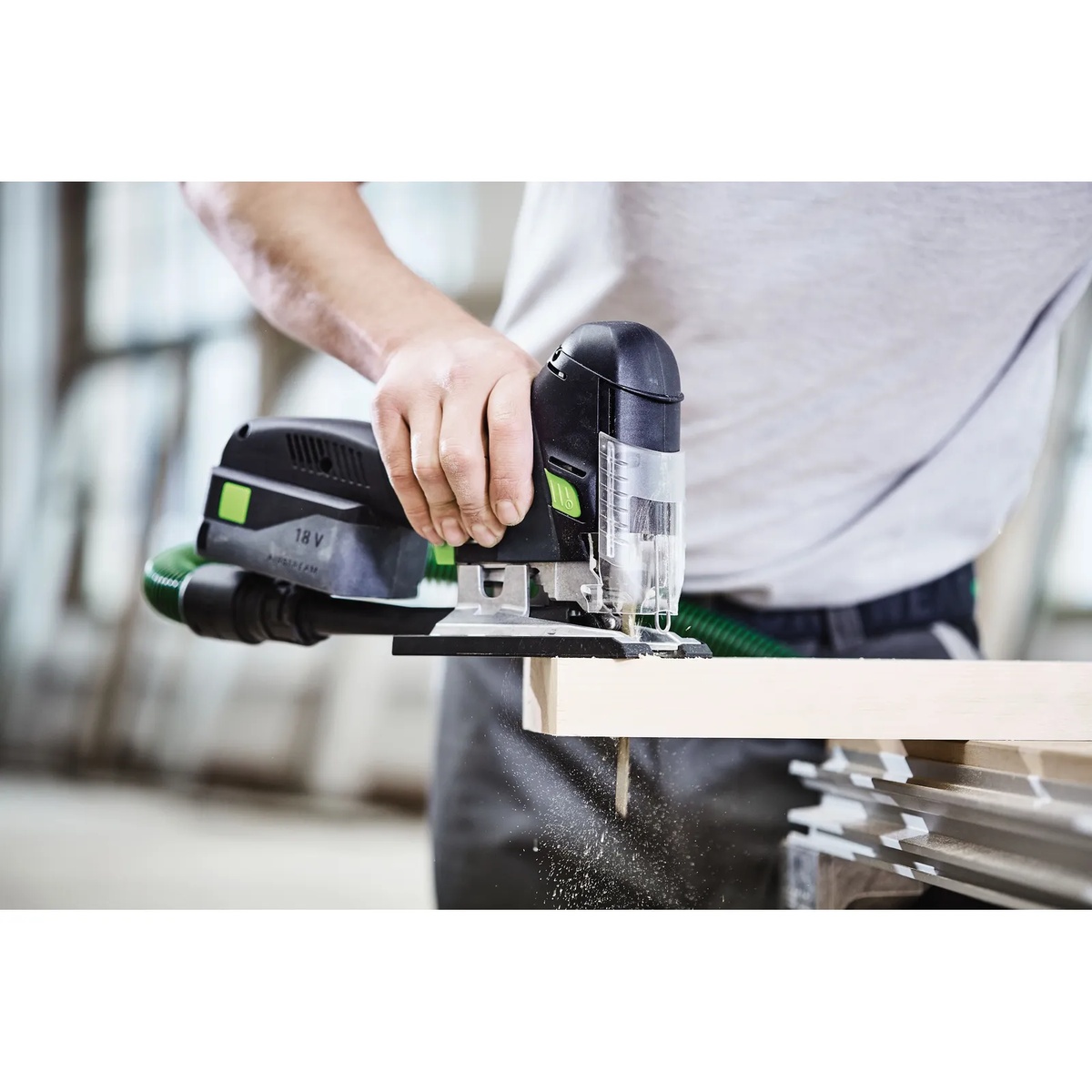 Festool 576527 PSC 420 EB Cordless Carvex Jigsaw Bluetooth 4.0Ah Kit with Systainer3 making a controlled cut in a wood board on a workbench with dust extraction connected on a jobsite-style setup