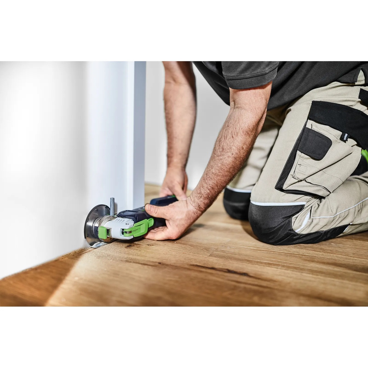Festool 576589 Vecturo OSC 18 StarlockMax Cordless Multi-Tool BASIC trimming at floor level near a wall during finish flooring installation