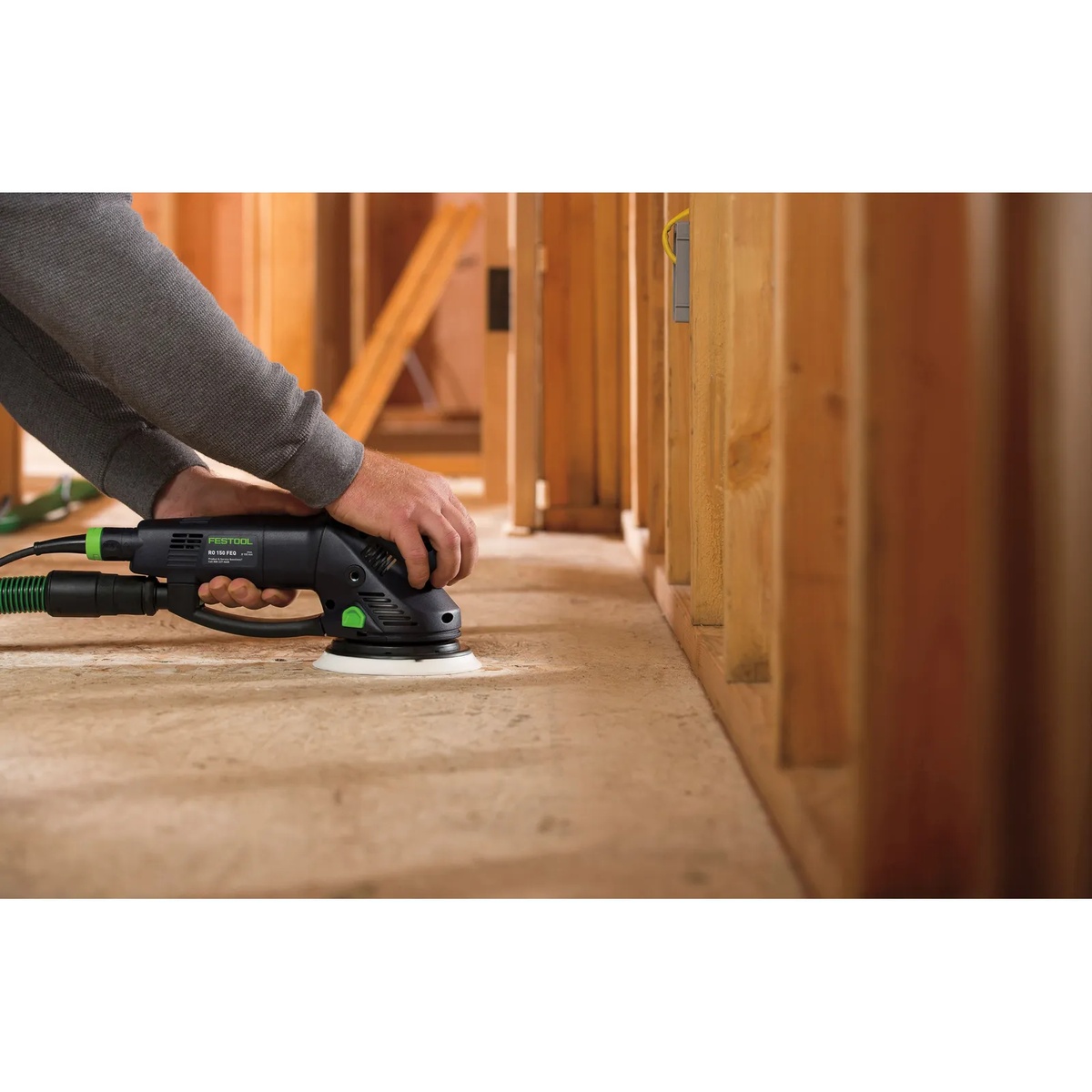 Festool 576028 RO 150 150mm (6 inch) FEQ Rotex Sander sanding close to a wall on a jobsite subfloor with dust extraction attached