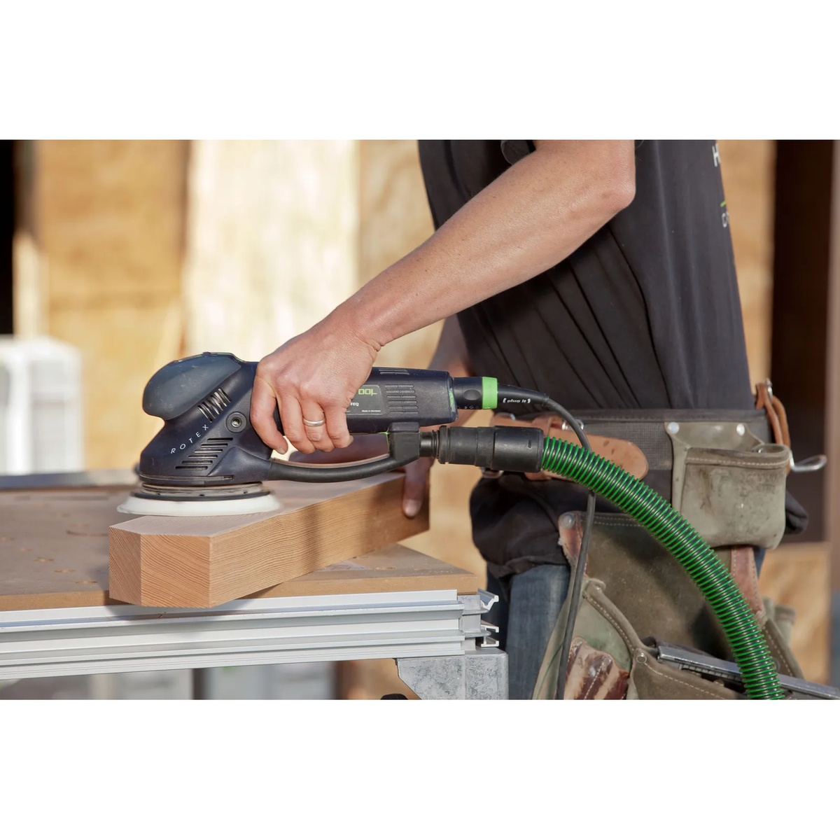 Festool 576028 RO 150 150mm (6 inch) FEQ Rotex Sander smoothing a wood block on a work table with a dust hose connected