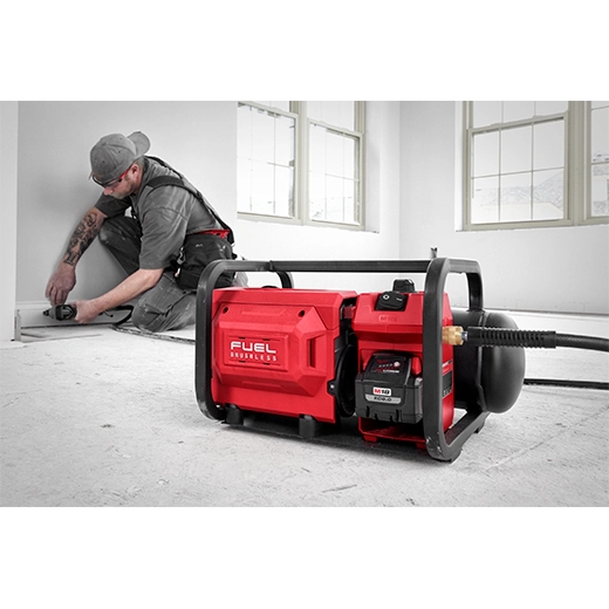 Milwaukee 2840-20 M18 FUEL 2 Gallon Compact Quiet Compressor on a remodel floor near a carpenter using a nailer for finish work