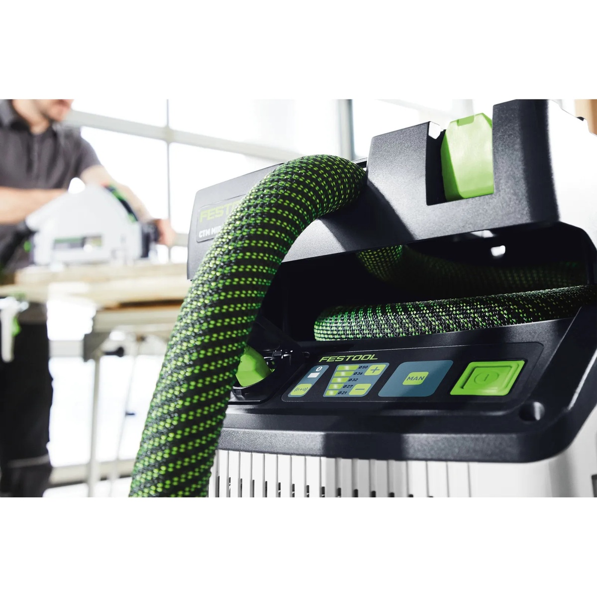 Festool 204923 Anti-Static Suction Hose D36/32x3.5m connected to a Festool dust extractor during shop cutting work, showing the hose routed into the extractor for active dust collection
