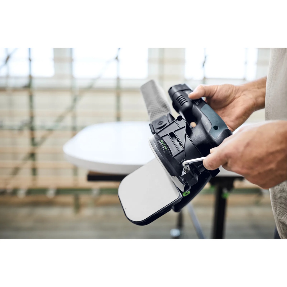 User adjusting the Festool 205316 Edge Sanding Guide for ETS/ETSC 125 Sanders with the included hex key before sanding a panel edge in a workshop