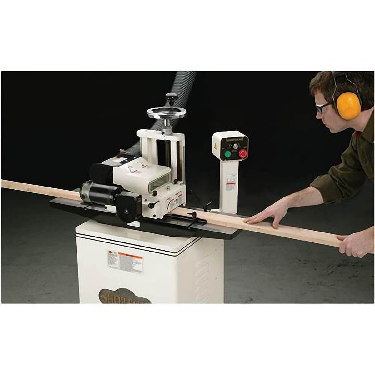 Shop Fox W1812 7-Inch Planer / Moulder with Stand feeding a long wood moulding board through the machine in a woodworking shop setup