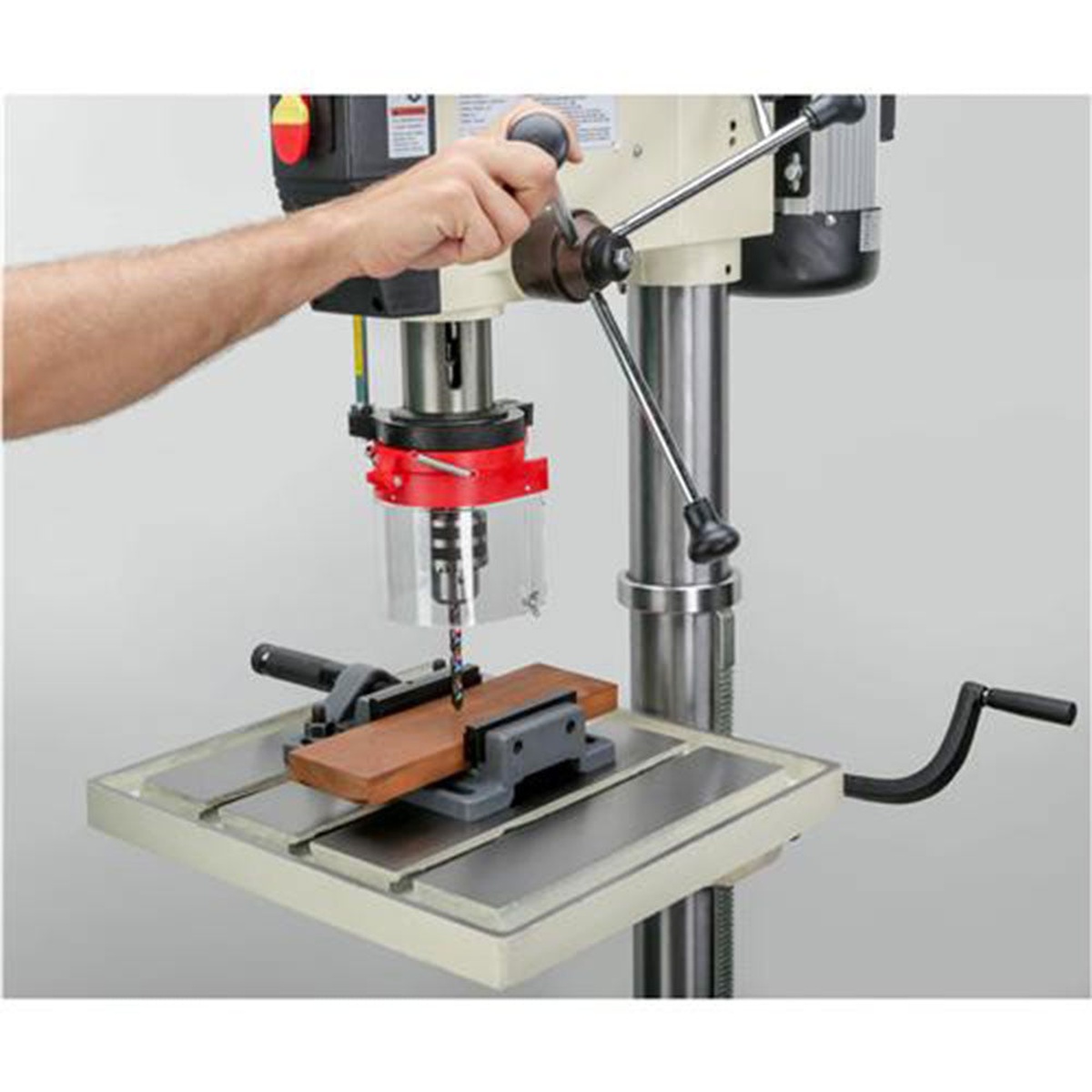 Shop Fox M1039 20 inch Professional Grade Floor Drill Press drilling a wood workpiece clamped in a vise on the cast iron table in a workshop setup