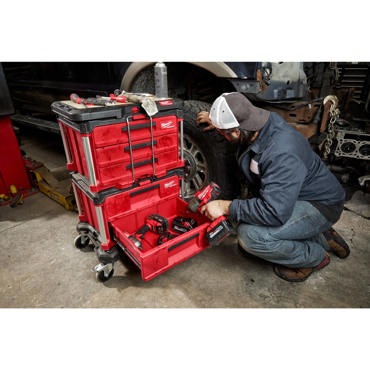 Milwaukee 48-22-8488 PACKOUT Customizable Work Top installed on a PACKOUT rolling storage stack in an automotive shop while a technician works beside the cart