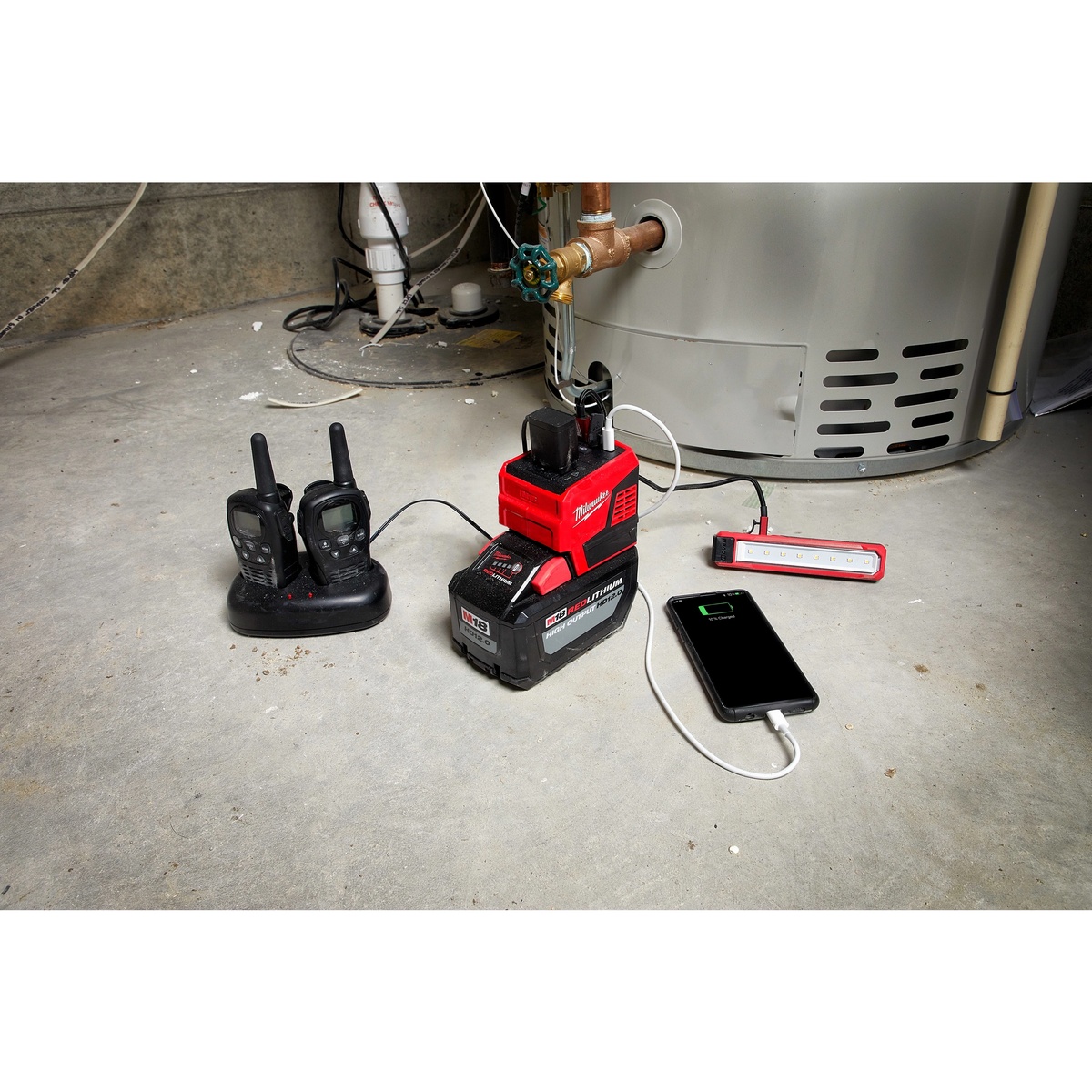 Milwaukee M18 TOP-OFF 175W Power Supply running chargers and a work light in a utility area beside a water heater during service work