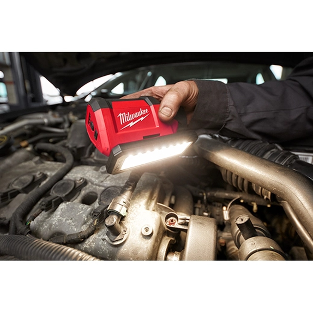 Milwaukee 2367-20 M12 ROVER Service and Repair Flood Light illuminating an automotive engine bay during repair work