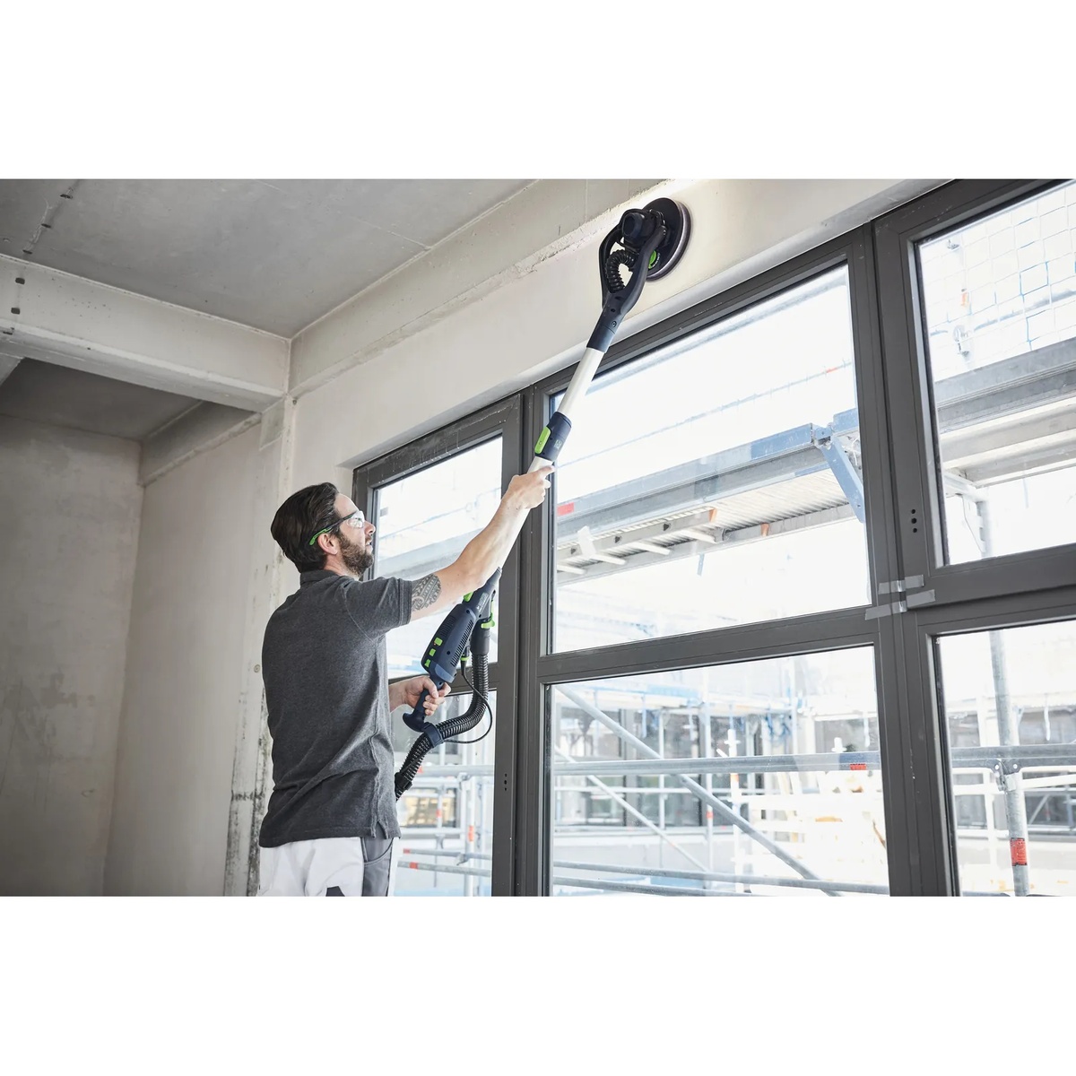 Festool LHS 2 225 EQI-Plus Drywall Sander smoothing drywall above a window opening during interior remodeling and ceiling edge finishing
