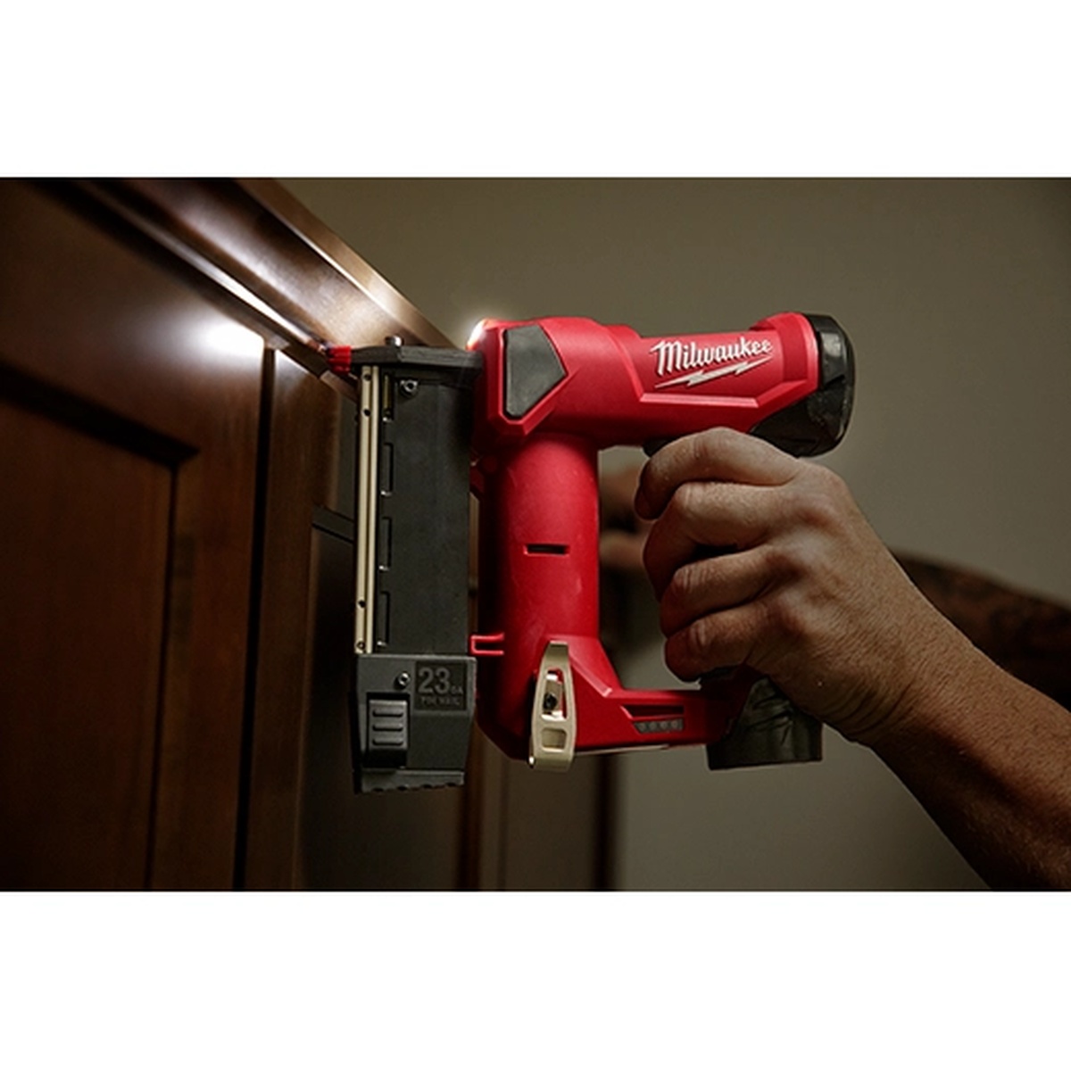 Milwaukee 2540-21 M12 23 Gauge Pin Nailer Kit driving a headless pin into cabinet trim in a finished interior space